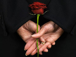 Woman Holding Red Rose Behind Back --- Image by © Bob Thomas/Corbis